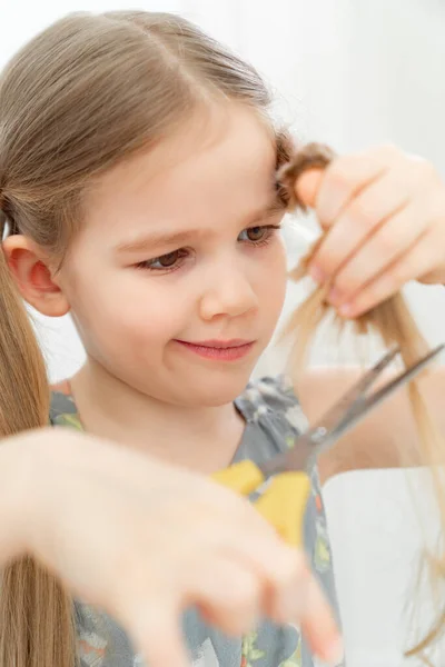 little girl cutting hair to herself with scissors