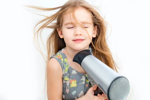 Kleines Mädchen trocknet ihre langen Haare mit einem Föhn — Stockfoto