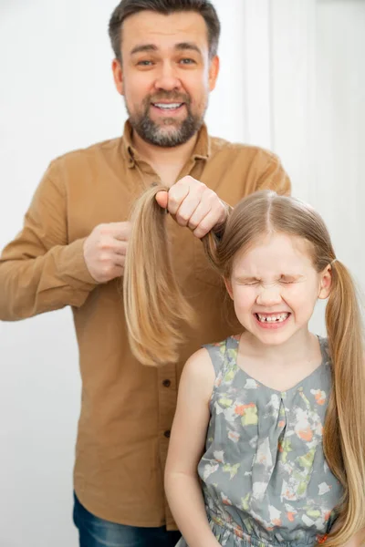 Papá hace colas de caballo de su pequeña hija — Foto de Stock