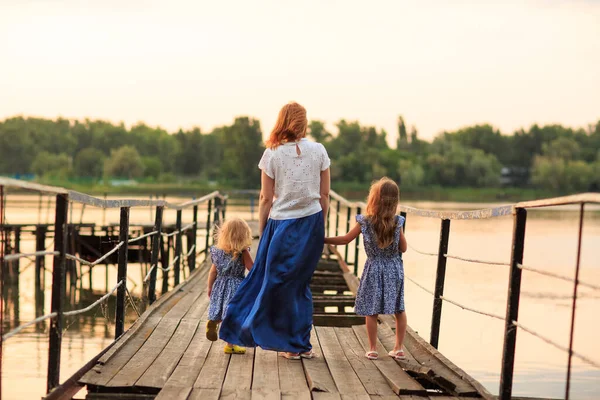 Мама и дети в синей одежде стоят старый мост — стоковое фото