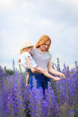 Anne ve kızı mor çiçeklerle tarlada