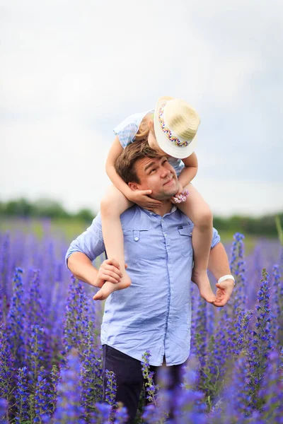 Pai e filha no campo com flores roxas — Fotografia de Stock