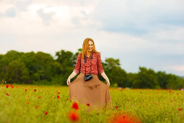 Mujer con pelo rojo dispara vídeo en el campo de amapola . — Foto de Stock