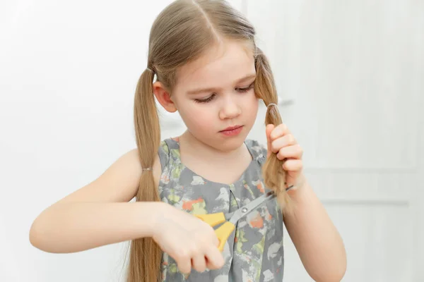 Petite fille coupe les cheveux à elle-même avec des ciseaux — Photo
