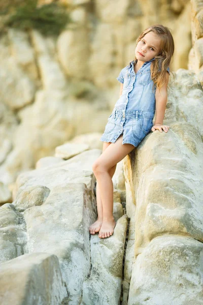 Маленькая девочка, сидящая на камне на закате. путешествия . — стоковое фото