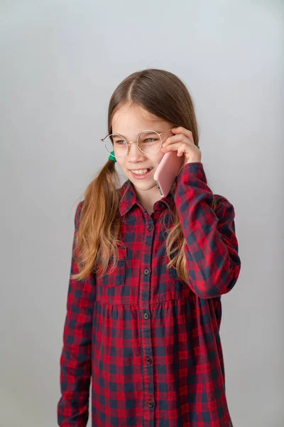 Söt flicka talar med mobiltelefon nära vit vägg — Stockfoto