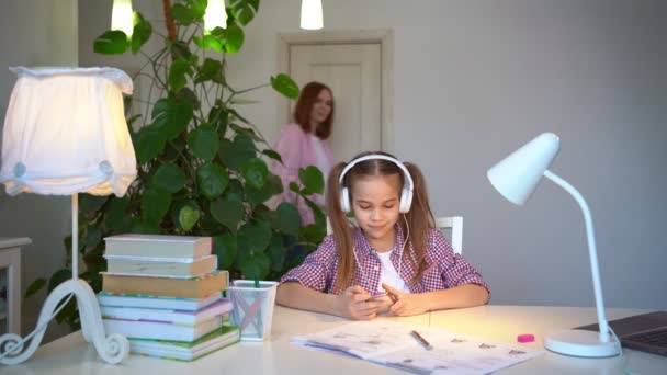 Школьница в наушниках слушает музыку — стоковое видео