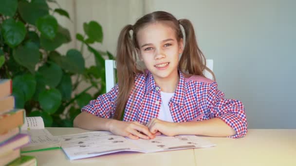 Schoolmeisje in een geruite shirt doet huiswerk — Stockvideo