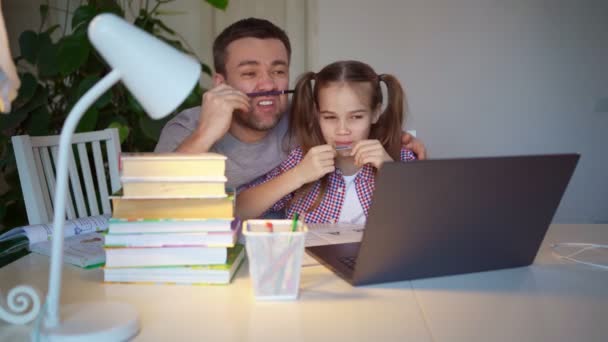 Папа играет и помогает дочери уроки на ноутбуке — стоковое видео