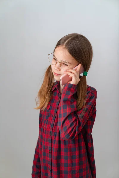 Schattig meisje praten door mobiele telefoon in de buurt van witte muur — Stockfoto