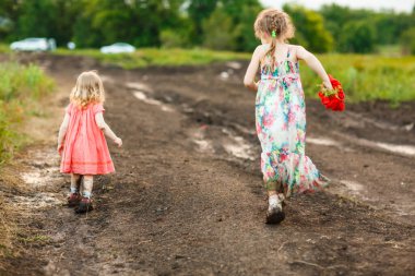 Arkadan bakan çocuklar yağmurdan sonra kirli yollara düşerler..