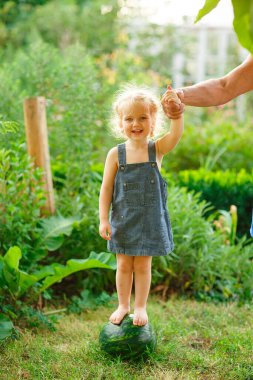 Çıplak bacaklı küçük kız karpuzun üzerinde duruyor..