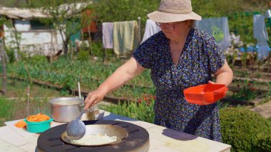 Kadın bahçede tandir 'de soğan kızartıyor..