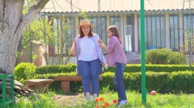 Anne ve kızı bahçede salıncakta.
