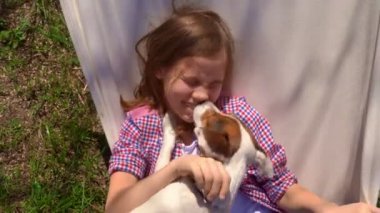 Genç kız bir köpekle hamakta yatıyor..