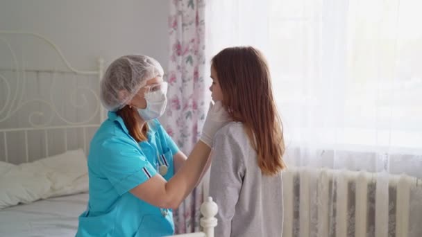 Läkare i mask undersöker barn hemma och kramar. — Stockvideo