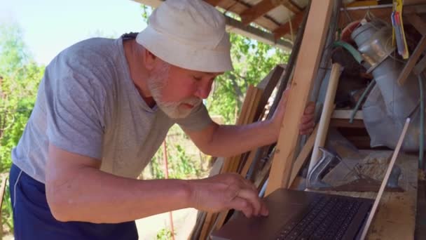 Homem idoso se comunica com um laptop na aldeia — Vídeo de Stock