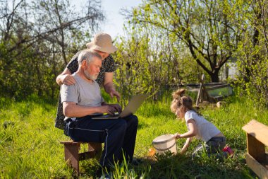 Köyde dizüstü bilgisayarı olan yaşlı bir adam ve kadın.