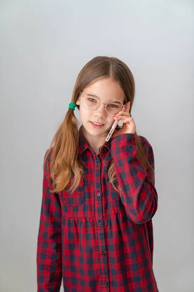 Menina bonito falando por telefone celular perto da parede branca — Fotografia de Stock