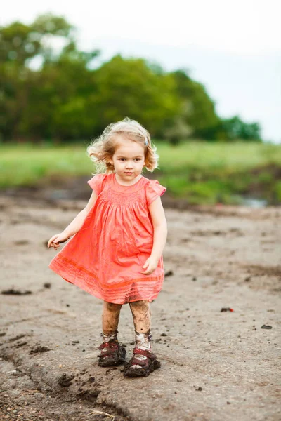 Маленькая девочка идет по грязной грунтовой дороге после дождя . — стоковое фото