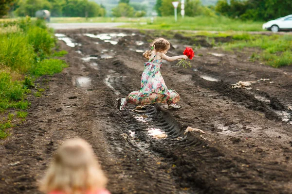 kid jumping through puddle road after rain