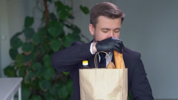 검은 장갑을 낀 사업가가 빵을 먹는다 — 비디오