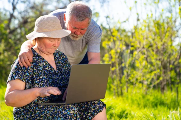 Elderly man and woman with a laptop in village