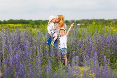 Anne ve kızları mor çiçeklerle tarlada