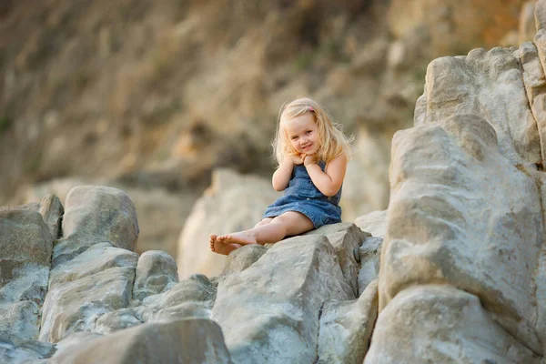Маленькая девочка, сидящая на камне на закате. путешествия . — стоковое фото