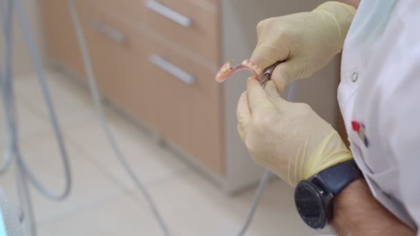 Mains dentiste ajuster la taille de la prothèse dentaire . — Video