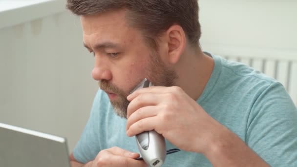 Człowiek robi fryzurę z brzytwy do brody w domu. — Wideo stockowe