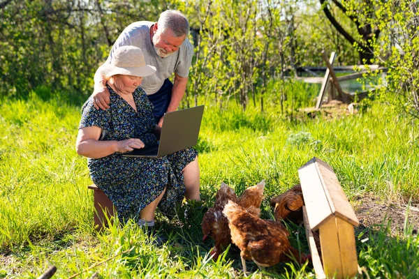 Anciano hombre y mujer con un portátil en la aldea — Foto de Stock