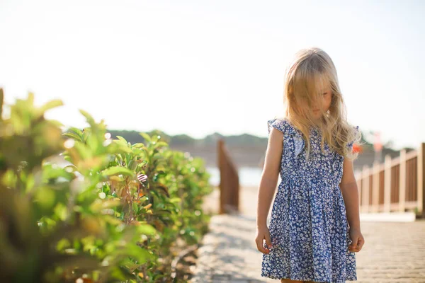 Smutná holčička v modrých šatech stojí na molu — Stock fotografie