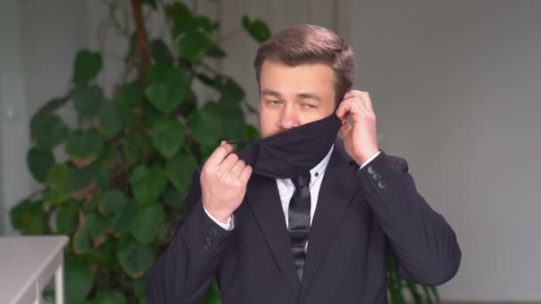 Obchodní muž v obleku nosí černou ochrannou masku — Stock video