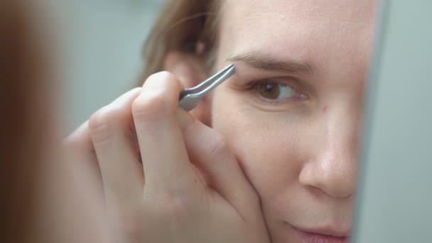 Kvinna gör korrigering av ögonbryn med pincett. — Stockvideo