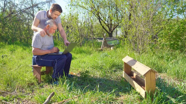 Hijo enseña padre anciano a trabajar en la computadora — Foto de Stock