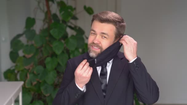 Smiling man in suit wearing black protective mask — Stock Video