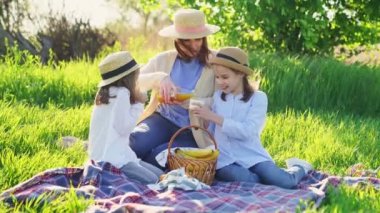 Çimenlikteki piknikte şapkalı bir anne..