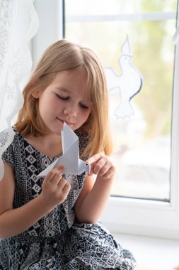 Çocuk pencerenin kenarında barışı simgeleyen güvercinlerle 