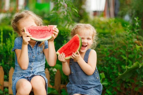 Little girls sit on watermelon and keep pieces — Stock Photo, Image