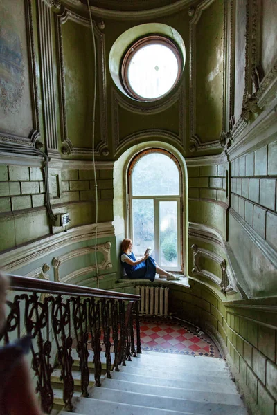 Frau sitzt aus Fenster in altem Haus und liest Buch — Stockfoto