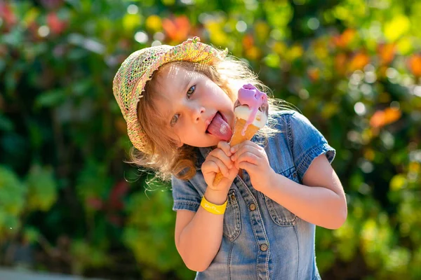 Little girl in hat eating ice cream on the street. — Stock Photo, Image