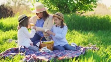 Çimenlikteki piknikte şapkalı bir anne..