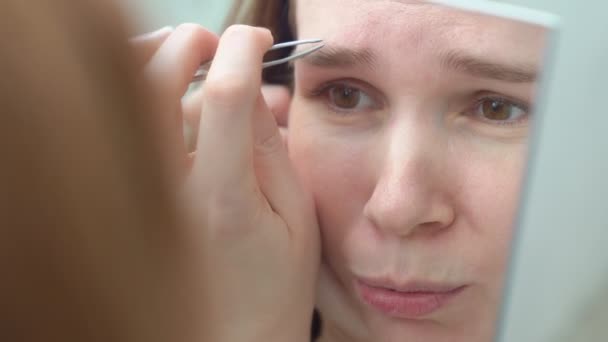 女性はピンセットで眉毛を矯正し. — ストック動画