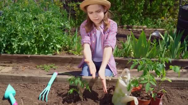Aantrekkelijk tiener meisje in hoed planten zaailingen — Stockvideo