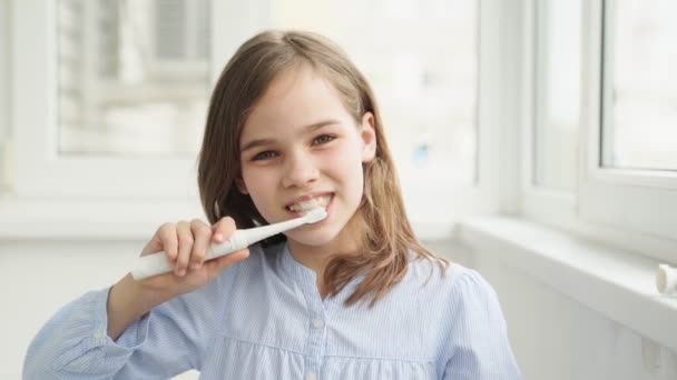 Chica limpia dientes cepillo de dientes eléctrico — Vídeos de Stock