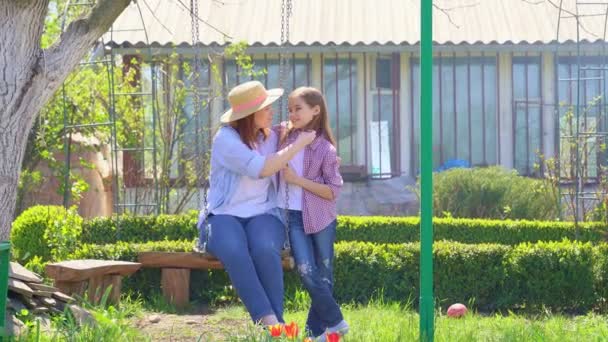Mom and daughter on swing in garden — Stock Video