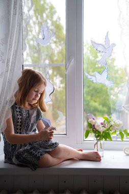 Çocuk pencerenin kenarında barışı simgeleyen güvercinlerle 