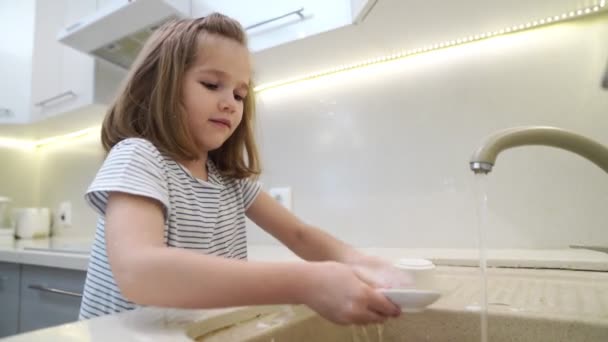 Grappig klein meisje doet de afwas. — Stockvideo