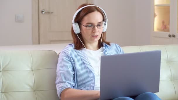 Frau arbeitet mit Kopfhörern am Computer — Stockvideo